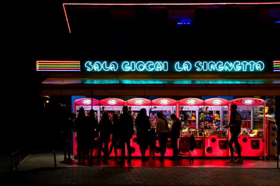 People enjoying a neon-lit arcade at night in Lido di Jesolo, Italy.