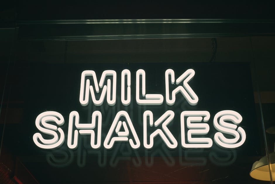 Close-up of an illuminated neon milk shakes sign in a dark setting.
